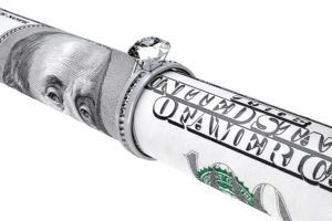 One hundred dollar bill in a diamond wedding ring on a white background