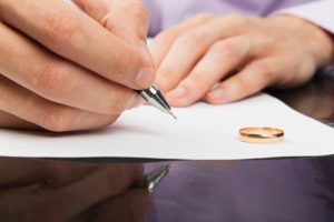 Closeup of male hand signing divorce papers