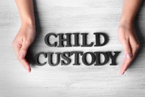 Human hands and words CHILD CUSTODY on wooden background, top view