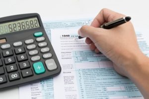 Filling out income tax forms with calculator and pen